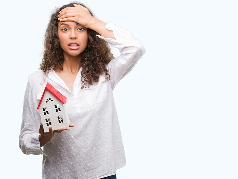 Woman holding a small house model, representing challenges in buying Aspen, CO condos.